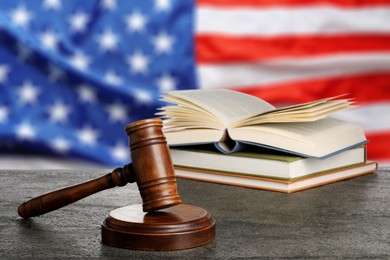 Image of Judge's gavel and books on grey table against flag of USA