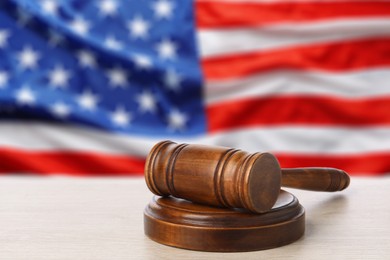Image of Judge's gavel on white table against flag of USA