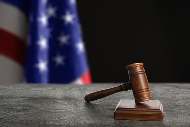 Image of Judge's gavel on grey table against flag of USA