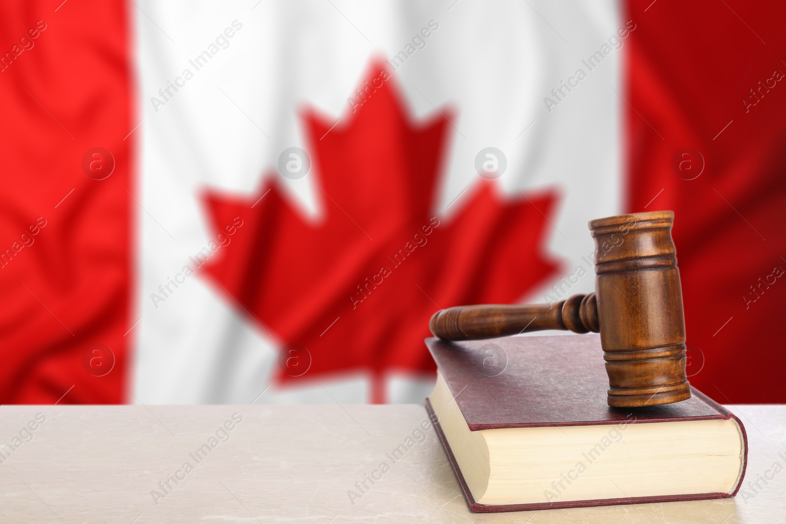 Judge's gavel and book on table against flag of Canada Image of Judge's gavel and book on table against flag of Canada