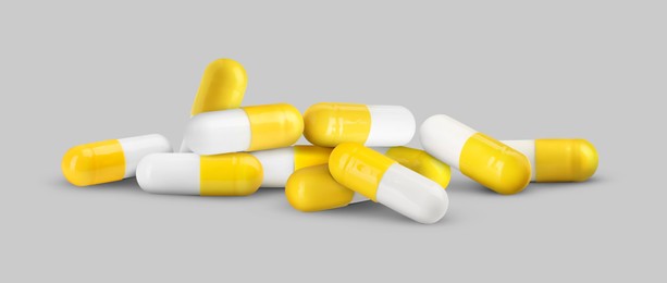 Image of Antibiotic pills. Yellow and white capsules on grey background. Banner design
