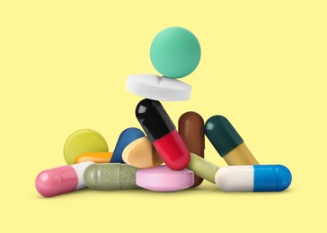 Image of Different antibiotic pills on pale yellow background