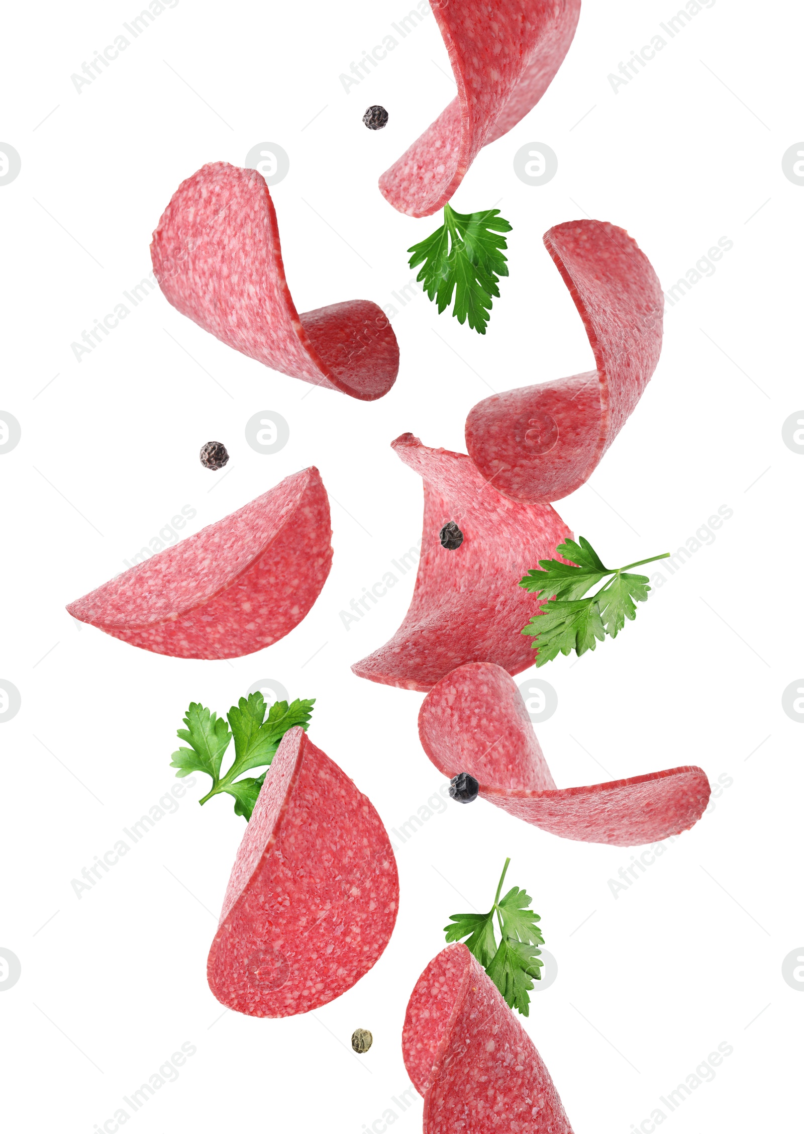 Salami sausage slices, peppercorns and parsley flying on white background Image of Salami sausage slices, peppercorns and parsley flying on white background
