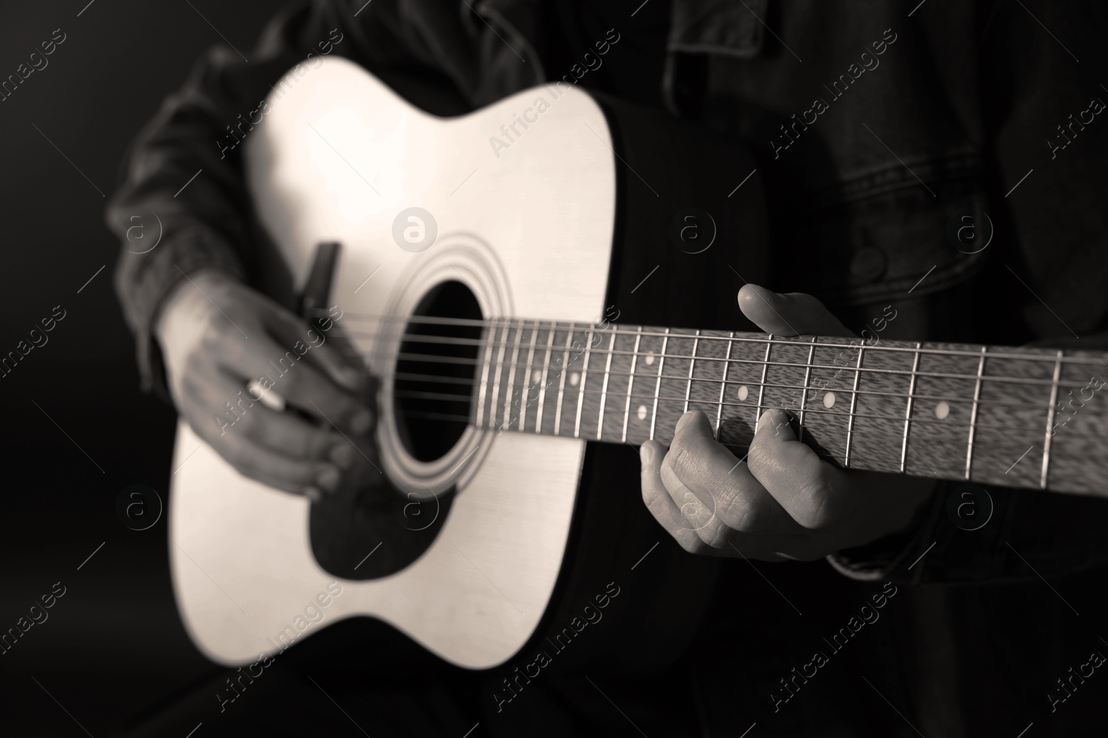 Man playing guitar in darkness, closeup. Black and white effect Image of Man playing guitar in darkness, closeup. Black and white effect