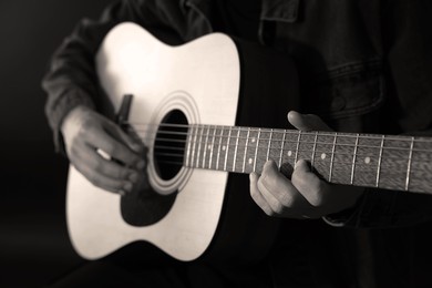 Image of Man playing guitar in darkness, closeup. Black and white effect