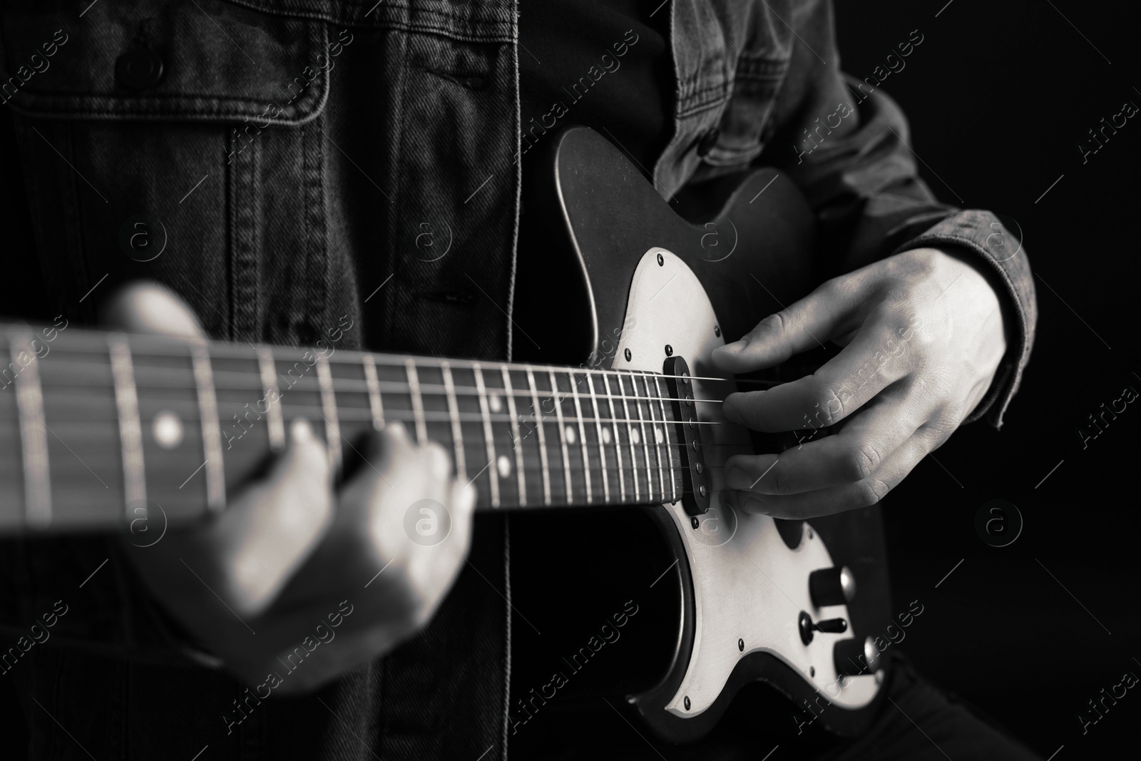 Man playing guitar in darkness, closeup. Black and white effect Image of Man playing guitar in darkness, closeup. Black and white effect