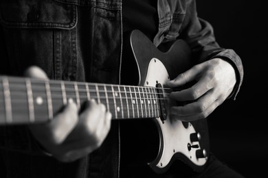 Image of Man playing guitar in darkness, closeup. Black and white effect