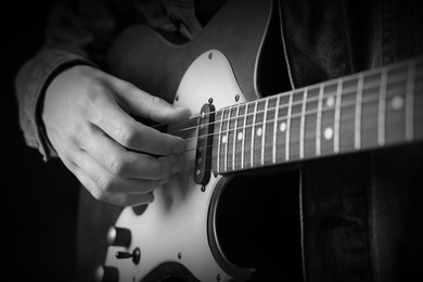 Image of Man playing guitar in darkness, closeup. Black and white effect