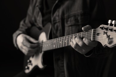 Image of Man playing guitar in darkness, closeup. Black and white effect