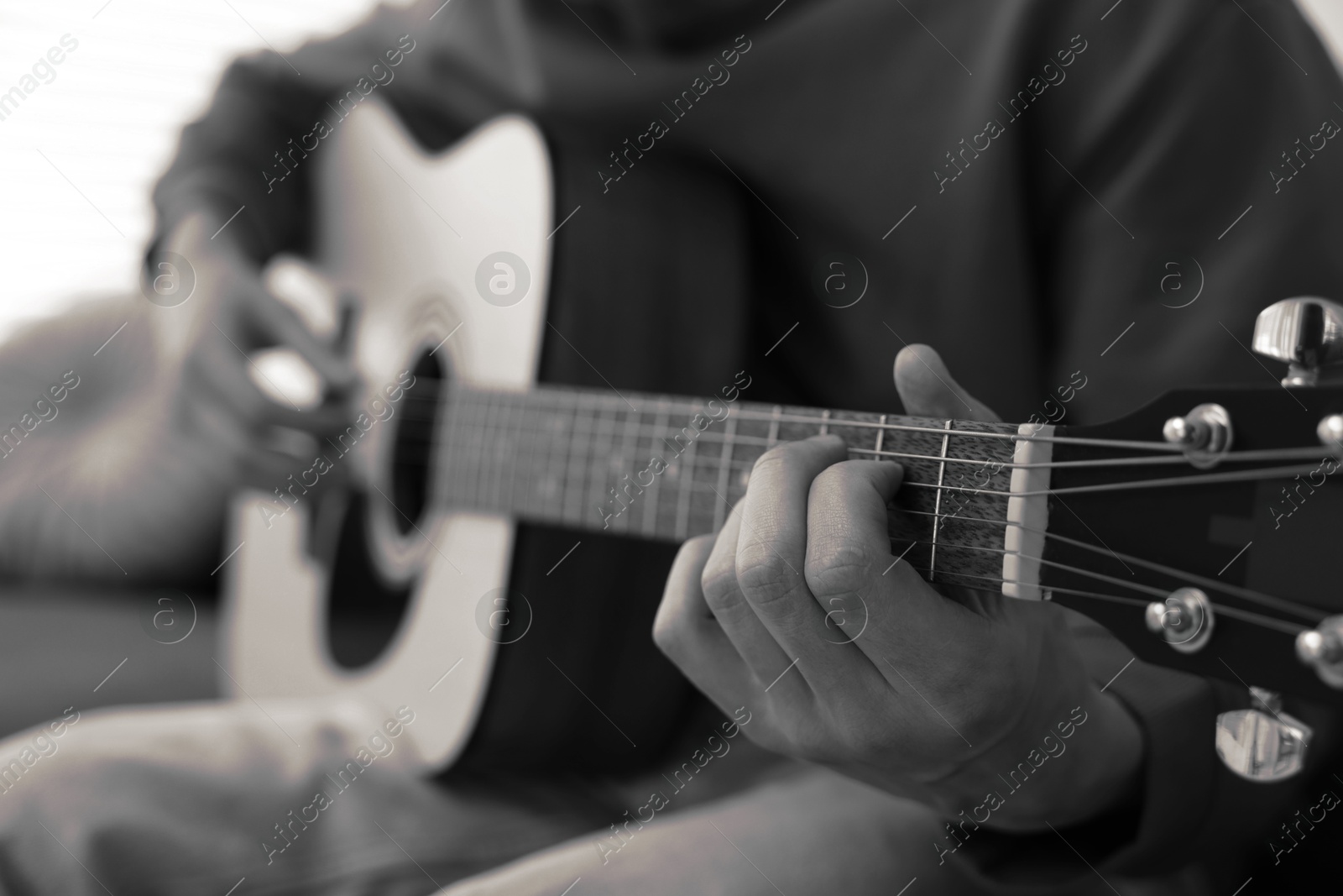 Man playing guitar indoors, closeup. Black and white effect Image of Man playing guitar indoors, closeup. Black and white effect