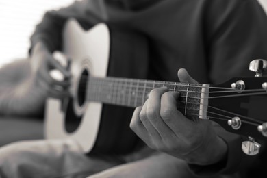 Image of Man playing guitar indoors, closeup. Black and white effect