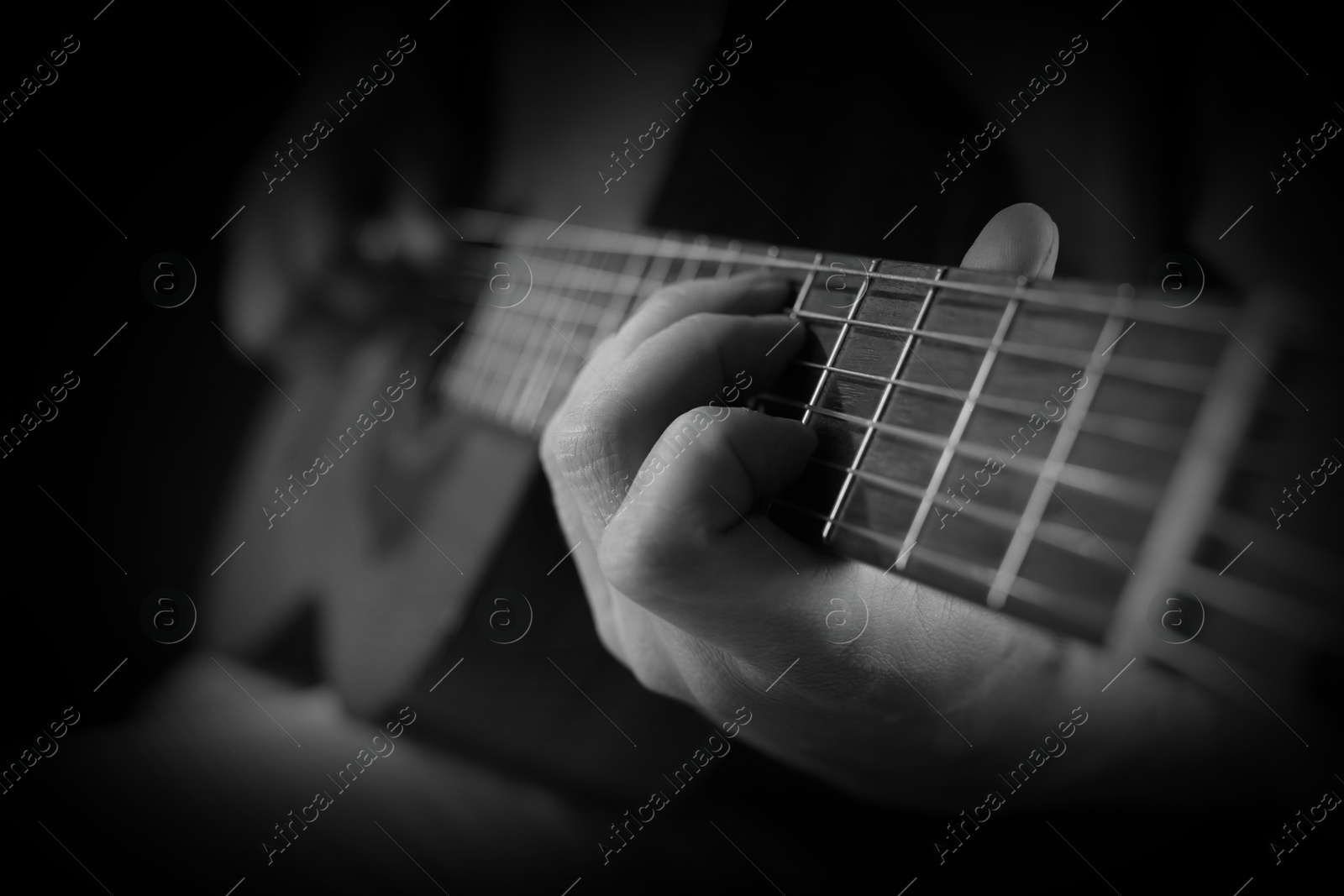 Man playing guitar in darkness, closeup. Black and white effect Image of Man playing guitar in darkness, closeup. Black and white effect
