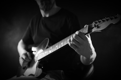 Image of Man playing guitar in darkness, closeup. Black and white effect
