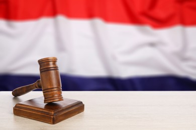 Image of Judge's gavel on wooden table against flag of Netherlands