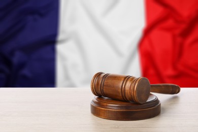 Image of Judge's gavel on wooden table against flag of France