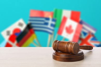 Image of Judge's gavel on wooden table against flags of different countries