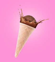 Image of Chocolate ice cream in waffle cone and splash of milk in air on pink background