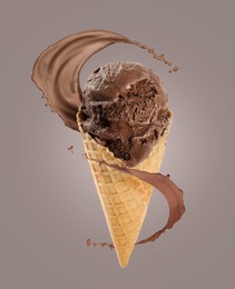 Image of Chocolate ice cream in waffle cone and splash of milk on grey background