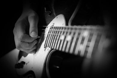 Image of Man playing guitar in darkness, closeup. Black and white effect