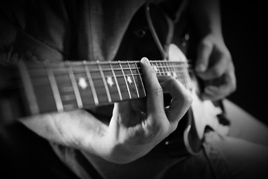 Image of Man playing guitar in darkness, closeup. Black and white effect