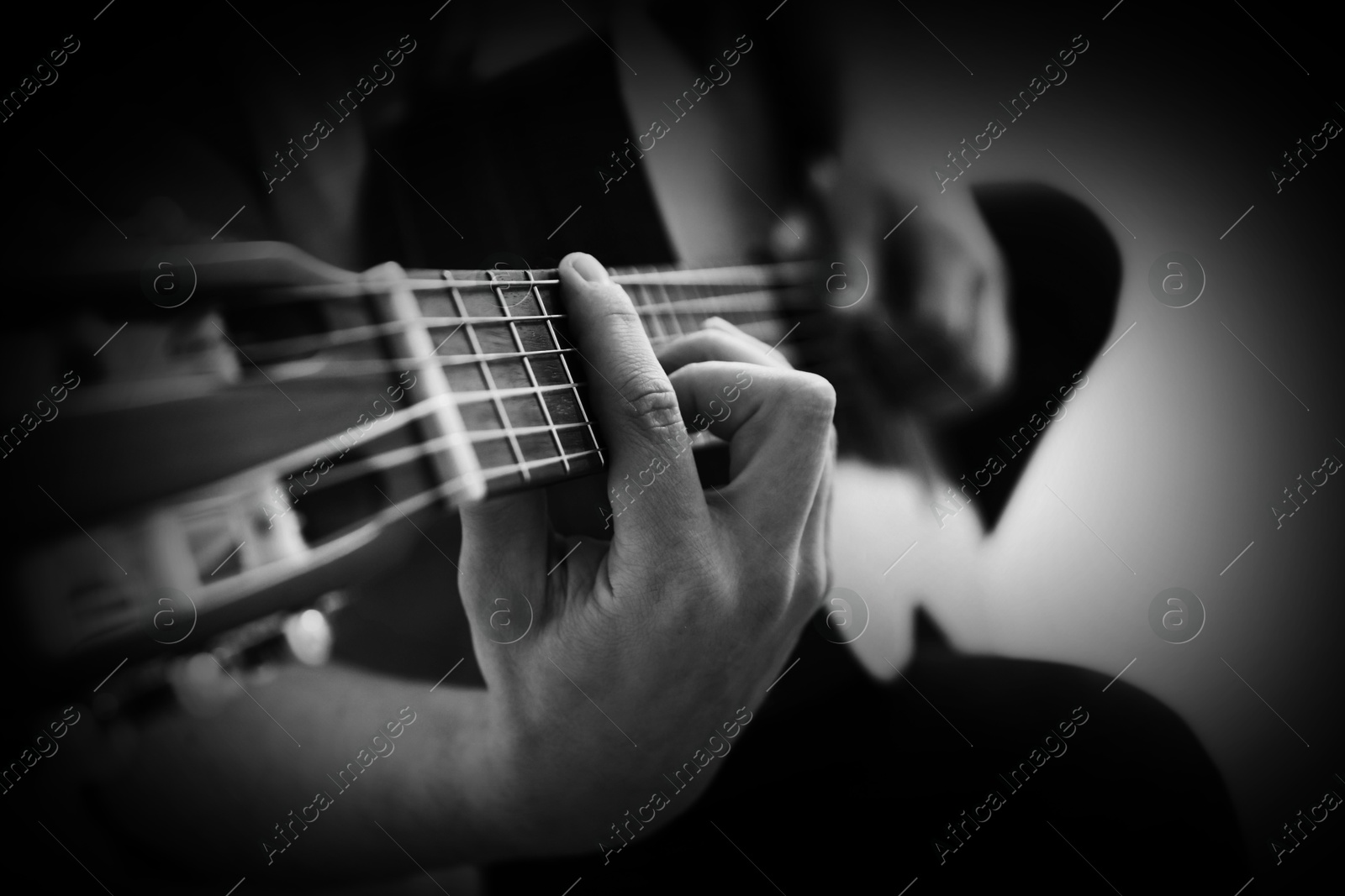 Man playing guitar on dark background, closeup. Black and white effect Image of Man playing guitar on dark background, closeup. Black and white effect