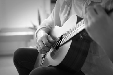 Image of Man playing guitar indoors, closeup. Black and white effect