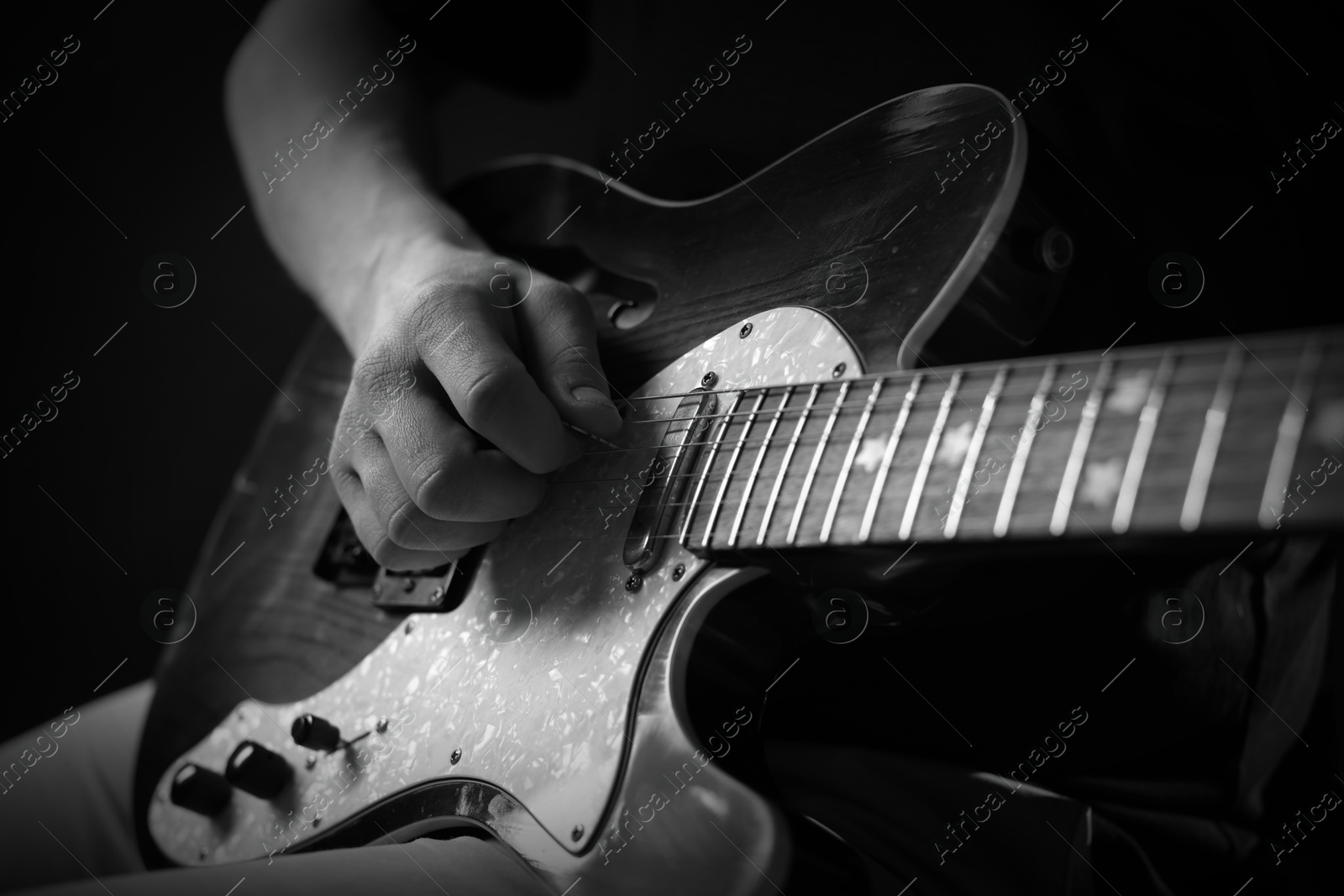 Man playing guitar in darkness, closeup. Black and white effect Image of Man playing guitar in darkness, closeup. Black and white effect