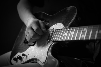 Image of Man playing guitar in darkness, closeup. Black and white effect