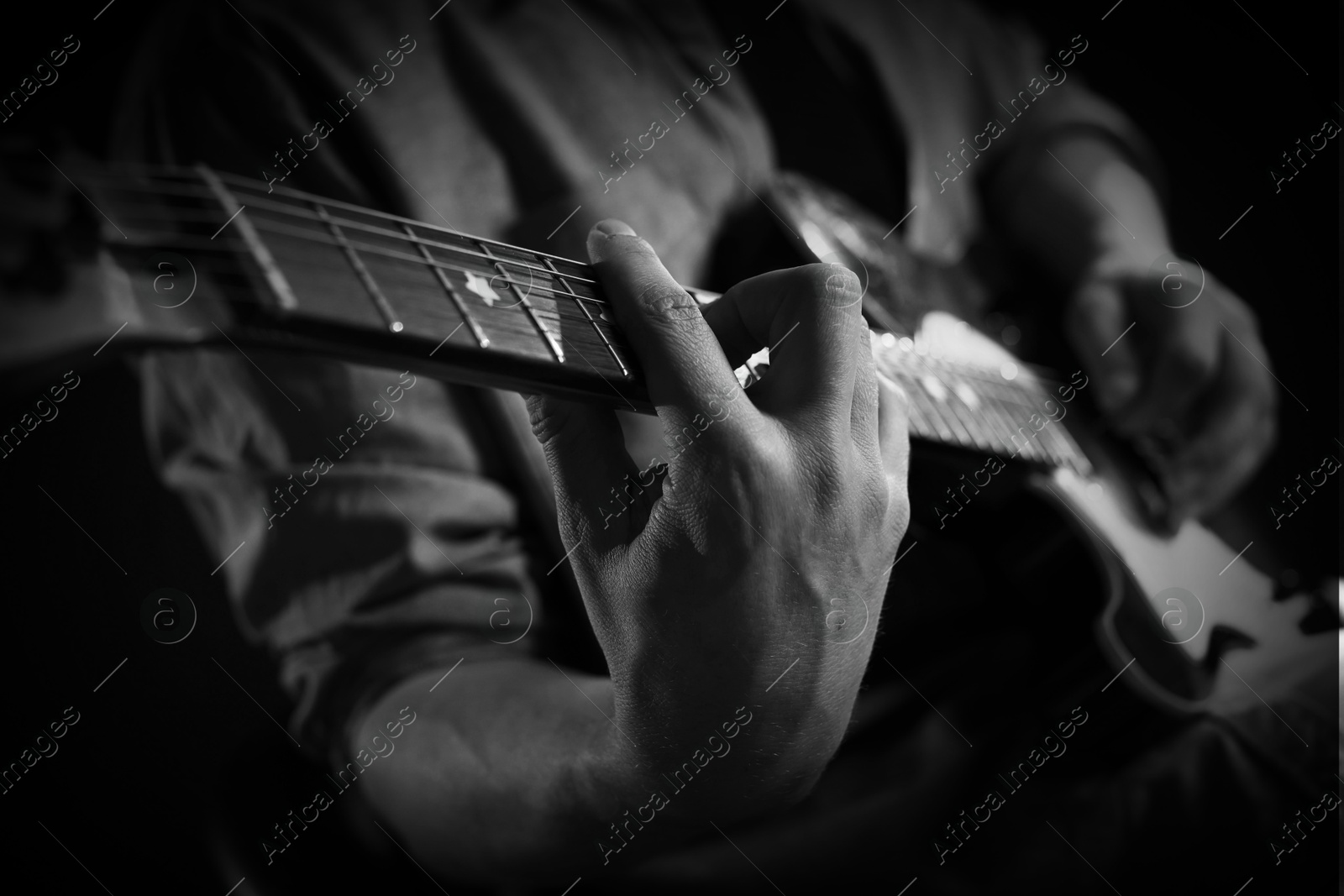 Man playing guitar in darkness, closeup. Black and white effect Image of Man playing guitar in darkness, closeup. Black and white effect