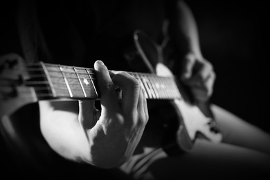 Image of Man playing guitar in darkness, closeup. Black and white effect