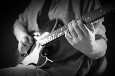 Image of Man playing guitar in darkness, closeup. Black and white effect