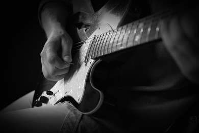 Image of Man playing guitar in darkness, closeup. Black and white effect