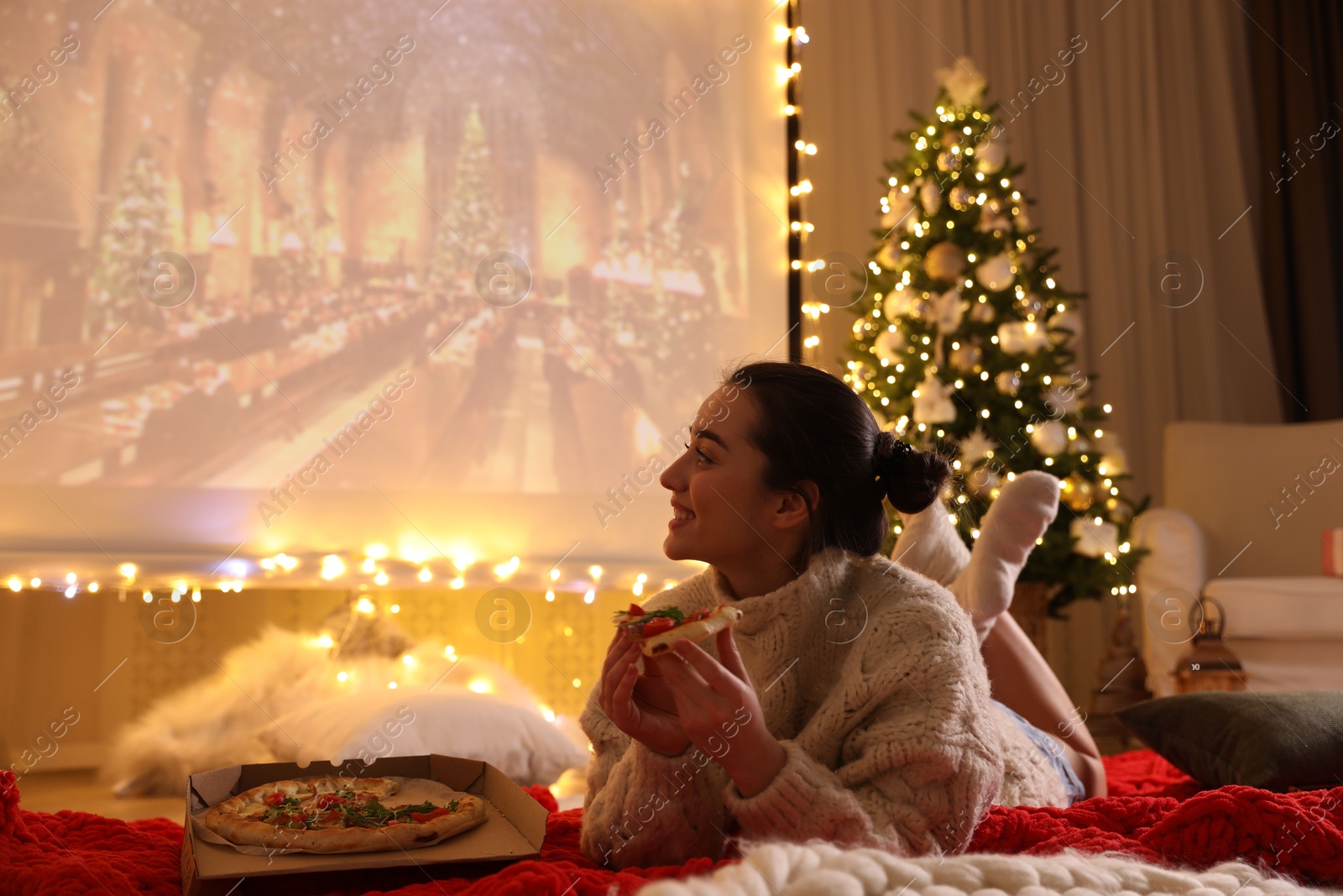 MYKOLAIV, UKRAINE - DECEMBER 24, 2020: Woman watching Harry Potter and Philosopher's Stone movie via video projector in room. Cozy winter holidays atmosphere Photo of MYKOLAIV, UKRAINE - DECEMBER 24, 2020: Woman watching Harry Potter and Philosopher's Stone movie via video projector in room. Cozy winter holidays atmosphere