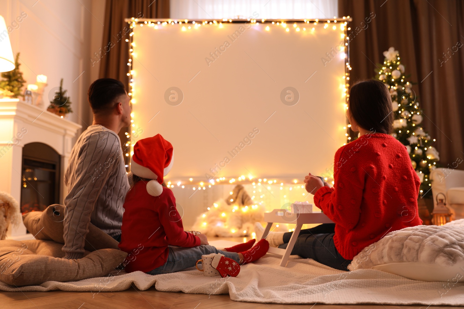 Photo of Family watching movie using video projector at home. Cozy Christmas atmosphere