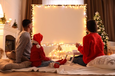Photo of Family watching movie using video projector at home. Cozy Christmas atmosphere