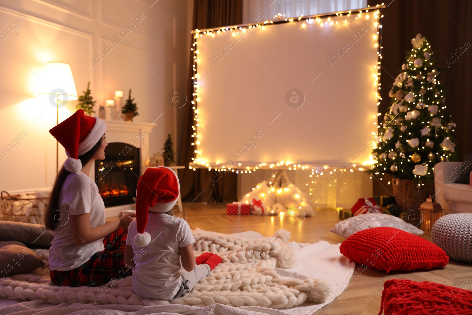 Mother and daughter watching movie using video projector at home. Cozy Christmas atmosphere Photo of Mother and daughter watching movie using video projector at home. Cozy Christmas atmosphere