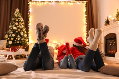 Photo of Family watching movie using video projector at home. Cozy Christmas atmosphere