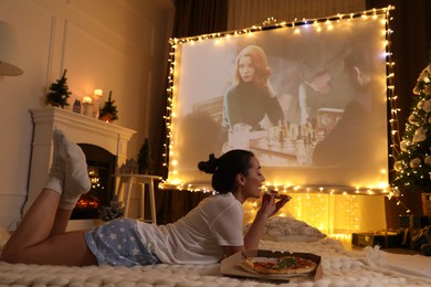 Photo of MYKOLAIV, UKRAINE - DECEMBER 24, 2020: Woman watching The Queen's Gambit series via video projector in room. Cozy winter holidays atmosphere