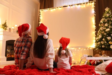 Photo of Family watching movie using video projector at home. Cozy Christmas atmosphere