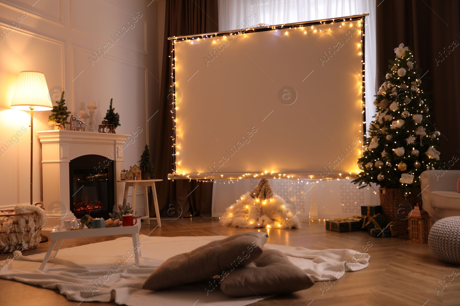Blank video projector screen in room decorated for Christmas. Cozy atmosphere Photo of Blank video projector screen in room decorated for Christmas. Cozy atmosphere