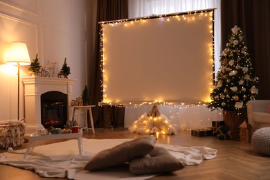 Photo of Blank video projector screen in room decorated for Christmas. Cozy atmosphere