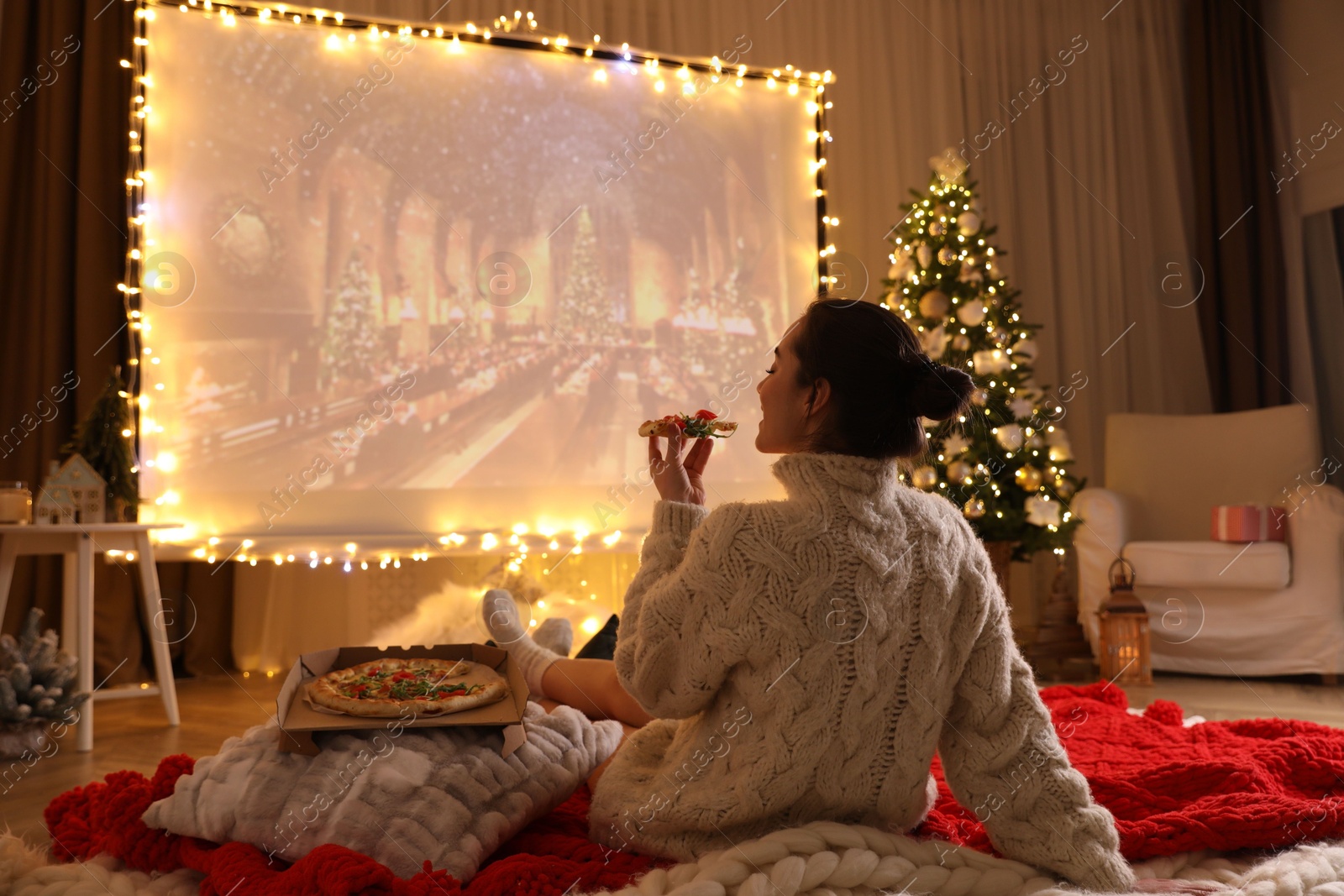 MYKOLAIV, UKRAINE - DECEMBER 24, 2020: Woman watching Harry Potter and Philosopher's Stone movie via video projector in room. Cozy winter holidays atmosphere Photo of MYKOLAIV, UKRAINE - DECEMBER 24, 2020: Woman watching Harry Potter and Philosopher's Stone movie via video projector in room. Cozy winter holidays atmosphere