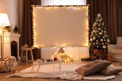 Photo of Blank video projector screen in room decorated for Christmas. Cozy atmosphere