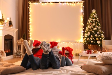 Photo of Family watching movie using video projector at home. Cozy Christmas atmosphere