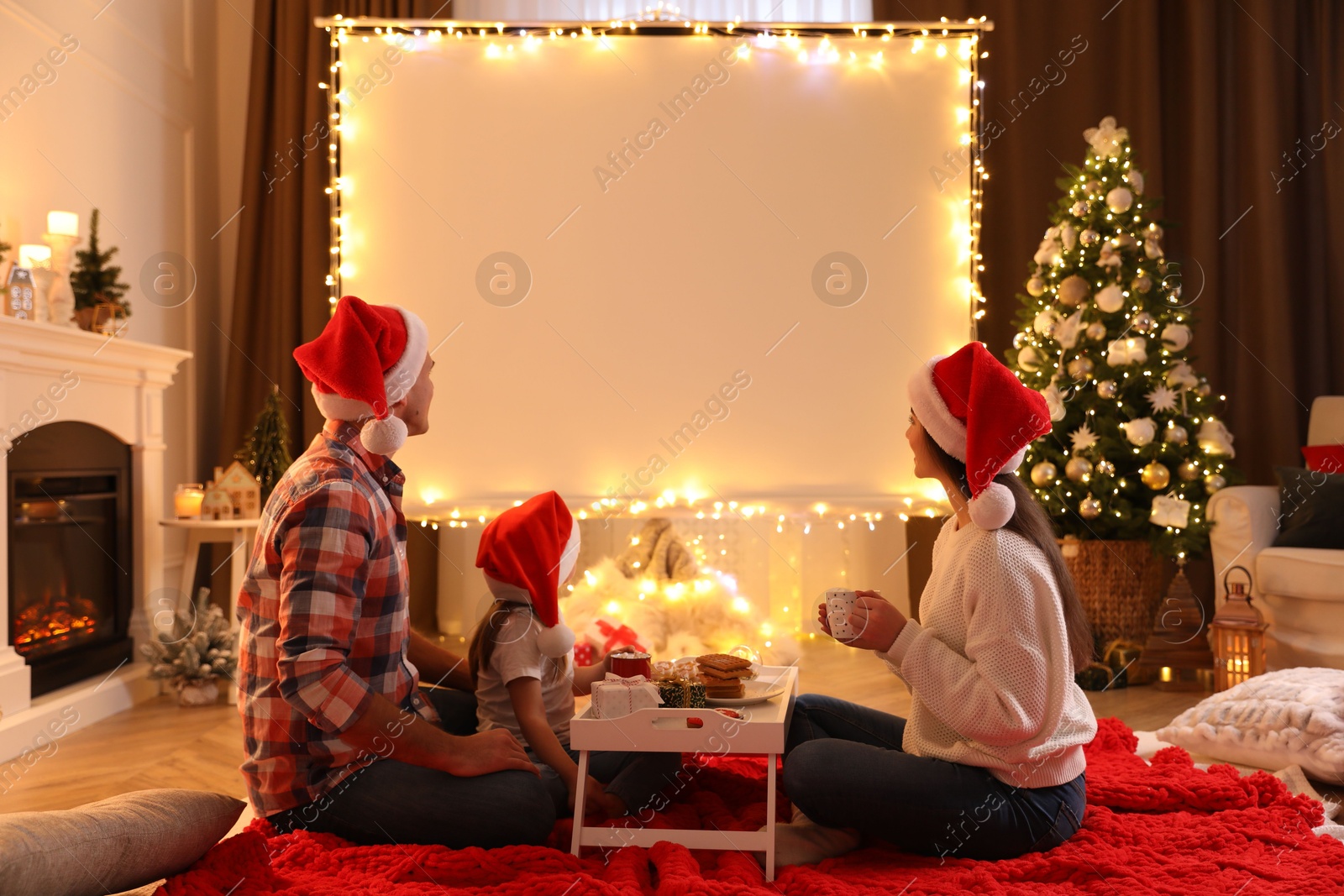 Photo of Family watching movie using video projector at home. Cozy Christmas atmosphere