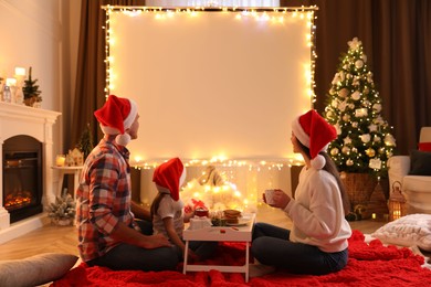 Photo of Family watching movie using video projector at home. Cozy Christmas atmosphere