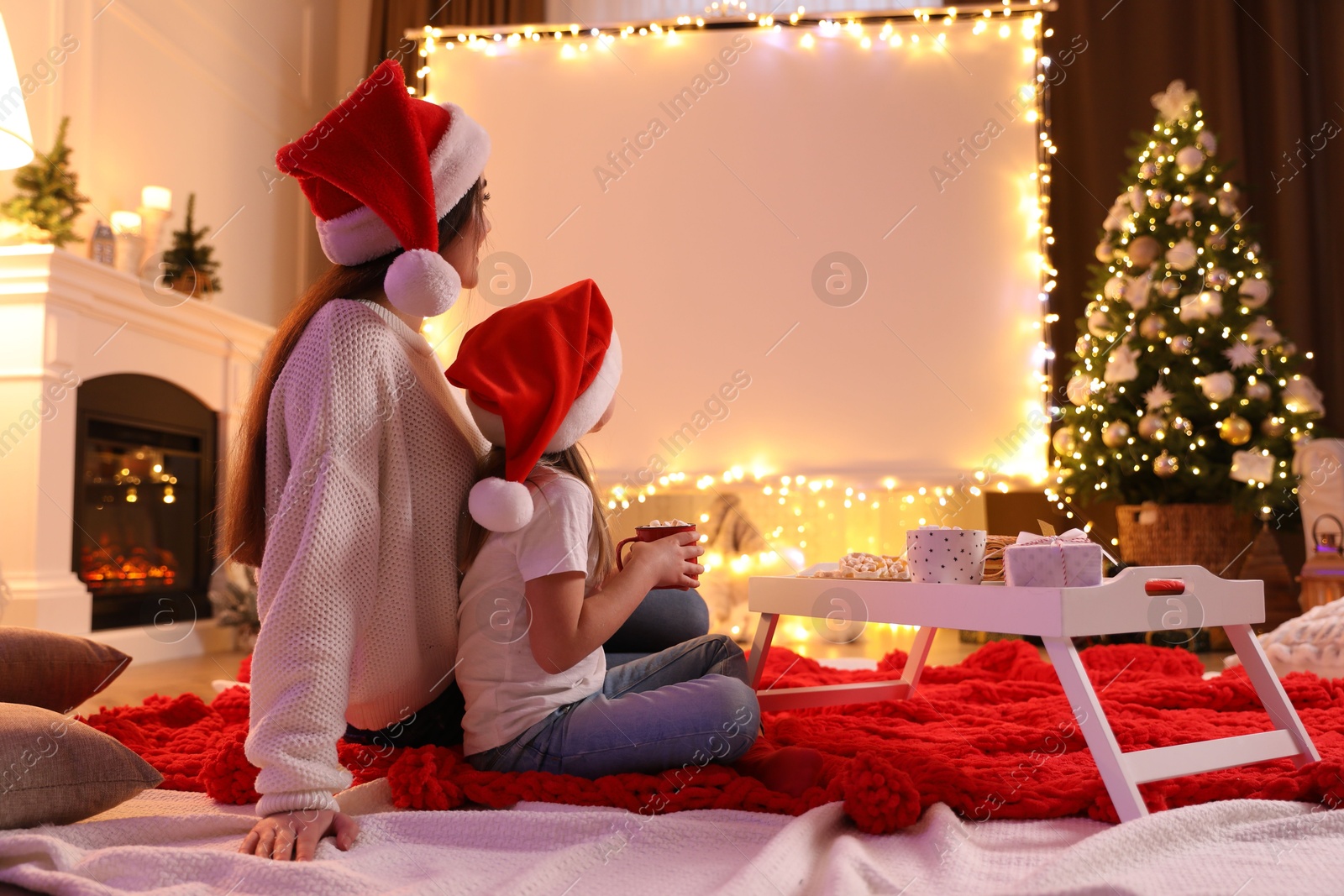 Mother and daughter watching movie using video projector at home. Cozy Christmas atmosphere Photo of Mother and daughter watching movie using video projector at home. Cozy Christmas atmosphere