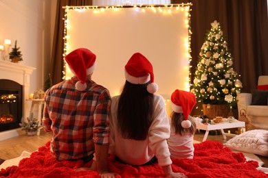 Photo of Family watching movie using video projector at home. Cozy Christmas atmosphere