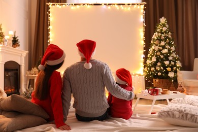Photo of Family watching movie using video projector at home. Cozy Christmas atmosphere