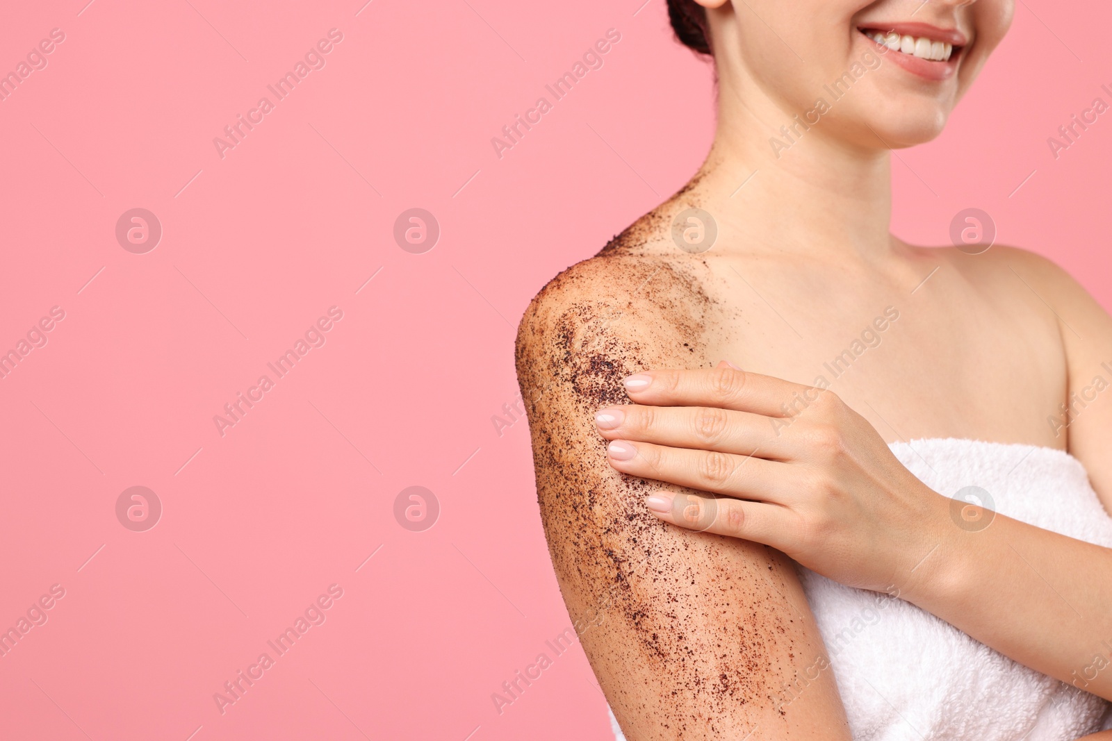 Smiling woman applying body scrub onto her arm against pink background, closeup. Space for text Photo of Smiling woman applying body scrub onto her arm against pink background, closeup. Space for text